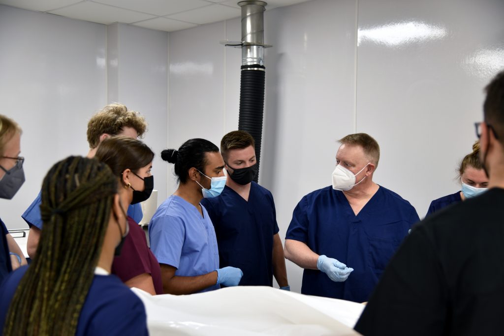 A group of students in anatomy lab being instructed by a professor.