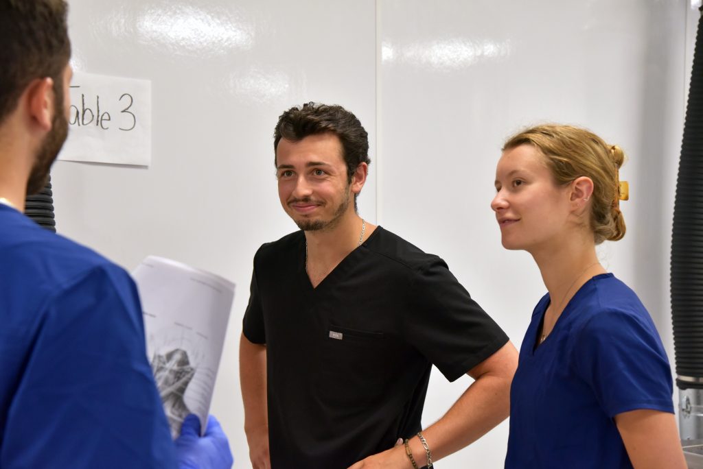 3 anatomy students talking, 1 is holding papers