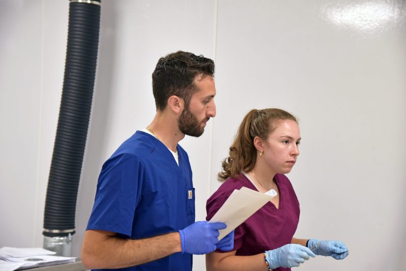 2 anatomy students, with 1 holding a folder.