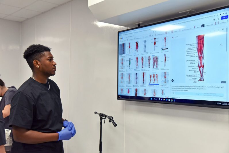 Student looking at SMART Board with view of leg muscles.